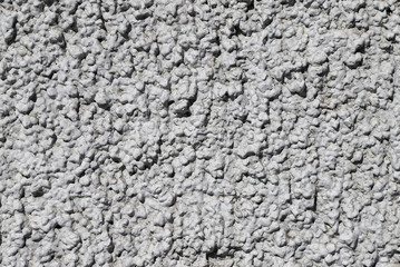 Texture of a wall made of crushed stone plastered with cement painted in gray