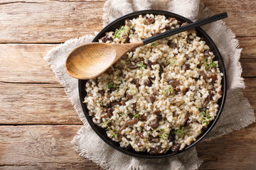 Healthy Orzotto cooked from pearl barley withporcini mushrooms close-up on a plate. Horizontal top...
