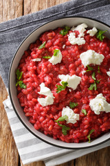 Italian Orzotto with beets, goat cheese and herbs close-up on a plate. Vertical top view