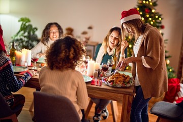 Beautiful group of women smiling happy and confident. Carving roasted turkey celebrating christmas at home