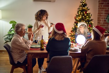 Beautiful group of women smiling happy and confident. On of them holding cup of wine speaking speech celebrating christmas at home