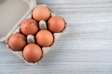 Closeup of raw chicken eggs in egg box on brown wooden background, organic food from nature good for health