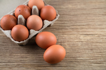 Closeup of raw chicken eggs in egg box on brown wooden background, organic food from nature good for health