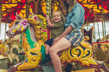 Little toddler on carousel with his mother