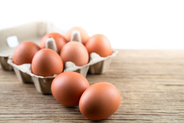 Closeup of raw chicken eggs in egg box on brown wooden background, organic food from nature good for health