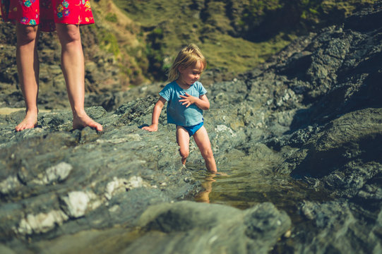 Little toddler playing in rockpools with his mother