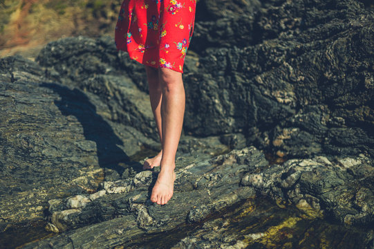 The legs and feet of a young woman on rocky beach