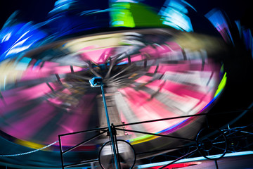 Amusement park ride fast spinning carousel roundabout with motion blur. Fun fair carnival  rides at...