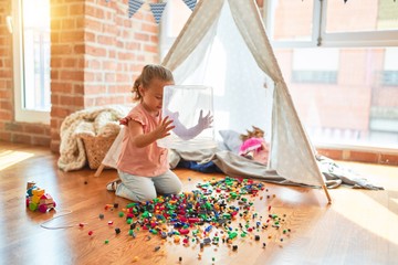 Beautiful blond toddler girl playing with constuction blocks outside tipi at kindergarten © Krakenimages.com