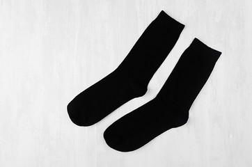Pair blank black tall socks side view flat lay on white wood board as mock up for design, print, presentation, advertising, top view, copy space.