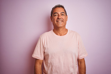 Handsome middle age man wearing t-shirt standing over isolated pink background with a happy and cool smile on face. Lucky person.