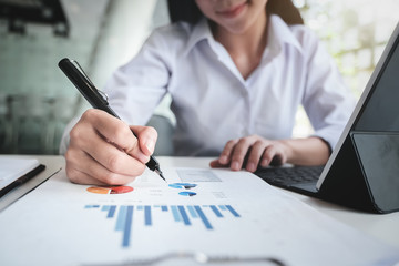 Business accounting , Business woman using tablet with calculate stock maket data chart, tax and budget paper in office. accounting auditor concepts.