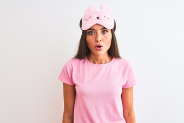 Young beautiful woman wearing sleep mask standing over isolated white background afraid and shocked with surprise expression, fear and excited face.