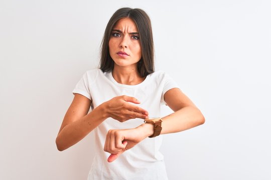 Young beautiful woman wearing casual t-shirt standing over isolated white background In hurry pointing to watch time, impatience, upset and angry for deadline delay