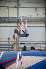 Pole vaulting - young woman is jumping over the high bar