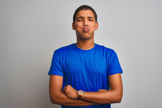 Young handsome arab man wearing blue t-shirt standing over isolated white background puffing cheeks with funny face. Mouth inflated with air, crazy expression.
