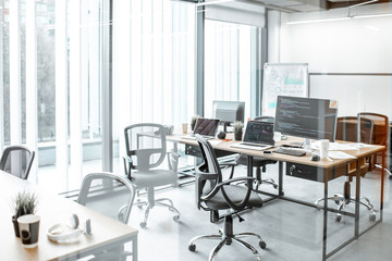 Working places with computers, gadgets and some documents on the table with no people in the modern coworking office