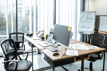 Working places with computers, gadgets and some documents on the table with no people in the modern coworking office