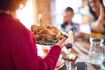 Beautiful family smiling happy and confident. One of them standing showing roasted turkey celebrating thanksgiving day at home