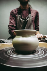 Fototapeta na wymiar Woman craftsman enjoying pottery art and production process. Making ceramic pot on potter's wheel.
