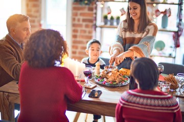 Beautiful family smiling happy and confident. One of them curving roasted turkey celebrating christmas at home