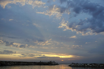 Amazing sunset view on the seashore. Wonderful blue sky, small clouds and the sun leaving the sky. A warm, quiet evening of a wonderful summer vacation at a beach resort.