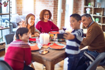 Beautiful family smiling happy and confident. Eating roasted turkey make selfie by smartphone celebrating christmas at home