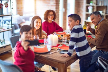 Beautiful family smiling happy and confident. Eating roasted turkey make selfie by smartphone celebrating christmas at home