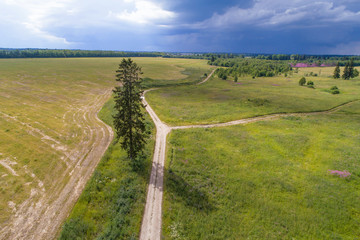 Country road in the July landscape before a thunderstorm (aerial photography). Leningrad region, Russia