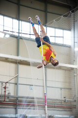 Pole vaulting - man with beard is reaching the bar on the pole