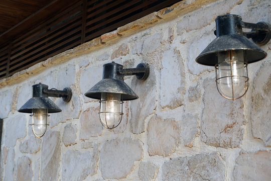 Three vintage street lamps on a rough stone wall. The texture of rough stone. Copy space.