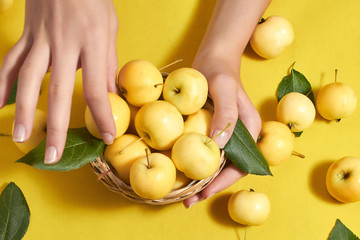 On a yellow background female hands apples. Skin care, proper nutrition!