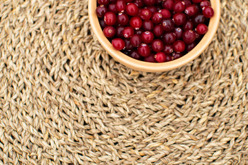 Authentic background, top view at wicker surface with bowl full of fresh cranberries standing at the table, morning at countryside
