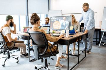 Group of diverse and creative colleagues working on computers in the modern office or coworking...