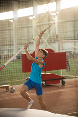 Pole vaulting - man in blue shirt is going to jump with pole