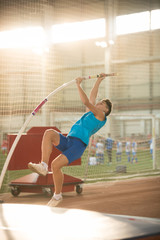 Obraz premium Pole vaulting - man is pushing the pole against the floor and starting his jump