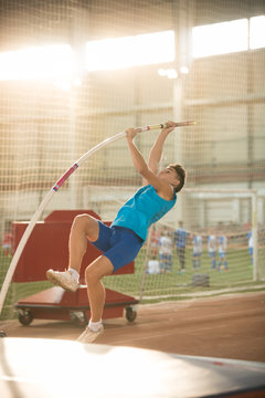Pole vaulting - man is pushing the pole against the floor and starting his jump