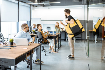 Courier delivering fresh lunches with thermal bag for an office workers. Concept of food delivery...