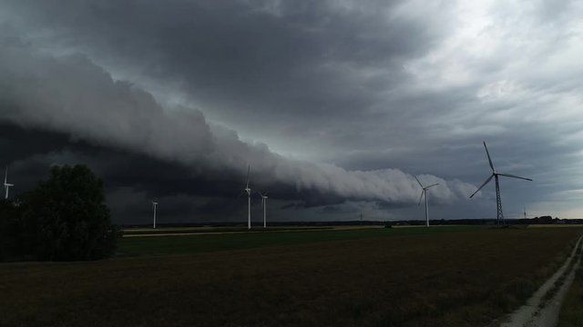 Drohne fliegt an Windkraftanlage vorbei w&auml;hrend eines Unwetters