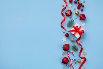 Gift or present box and holiday decorations on light blue background top view. Christmas or New year greeting card. Flat lay.