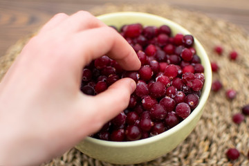 Eating nutrition food, female hand takes frozen berry from the bowl, winter food