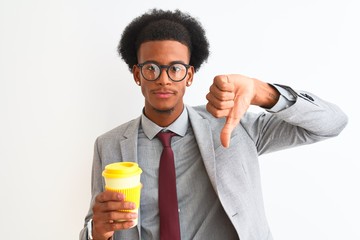 African american businessman drinking cup of coffee over isolated white background with angry face,...
