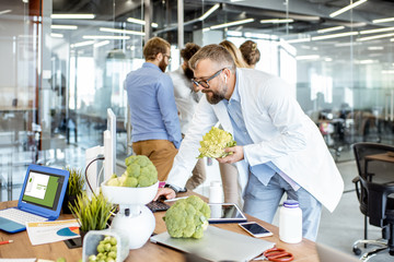 Senior nutritionist working on a diet plan at the working place with computer and fresh food in the...