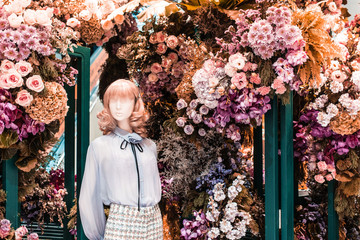 Fashion female clothes on mannequin in decorative flower booth