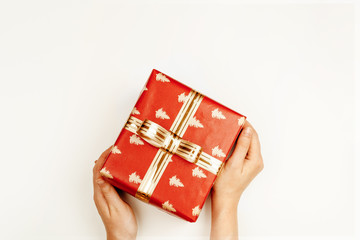 Wrapped Christmas gift in woman hands above white background