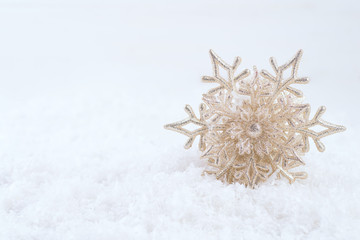 Gold Christmas decoration. Beautiful snowflake on snow background. Winter holidays concept