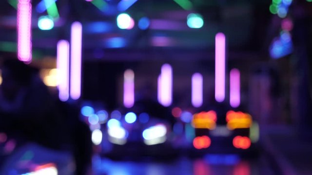 Blur bokeh effect showing illuminated riding and crashing bumper cars in real time