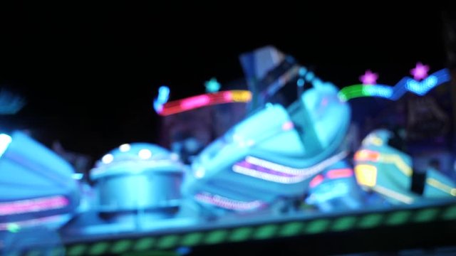 Illuminated high speed carousel spinning in circle,people dizzling,static close up
