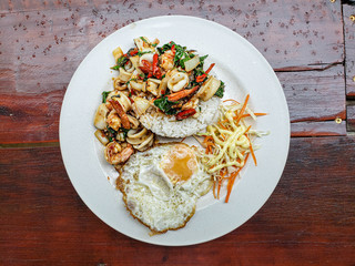 Stir fries seafood with chilis and Thai hot basil served with salad and mayonnaise dressing (Thai street food : Pad Kra Praow Talay)