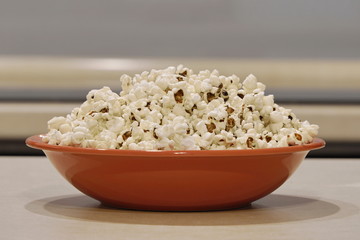 coral plate with popcorn on the table. a snack, a treat to the cinema or the circus. exploding corn kernels.